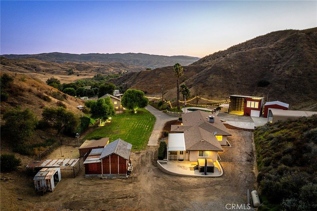 Wide dusk aerial of the compound showing barn, red outbuilding, and canyon drive