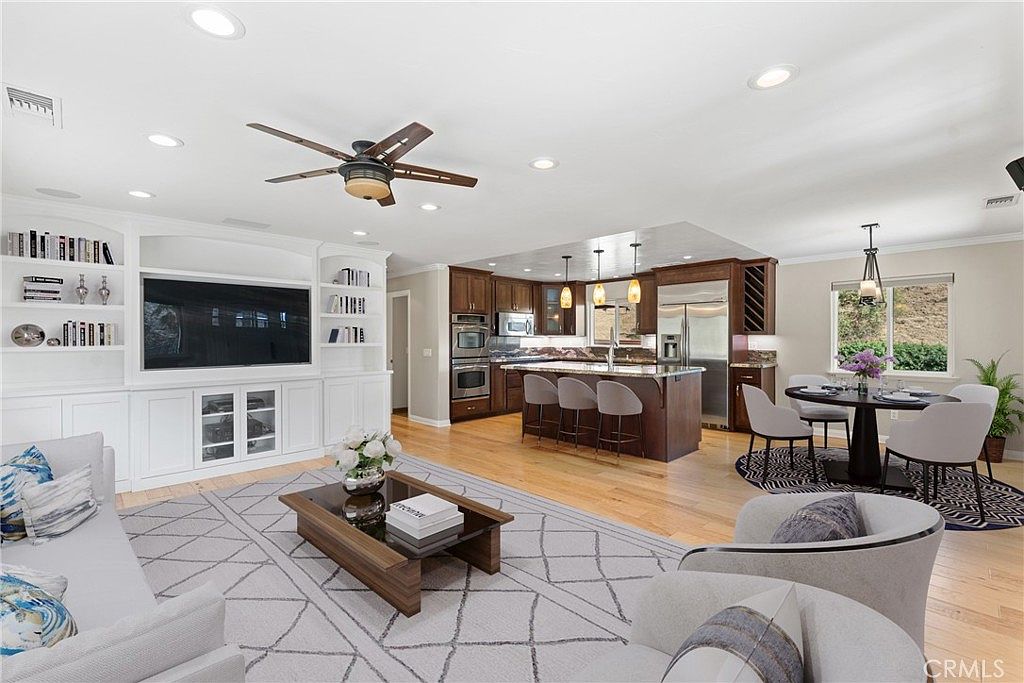 Open-concept living and kitchen with custom cabinetry, large island, wood floors