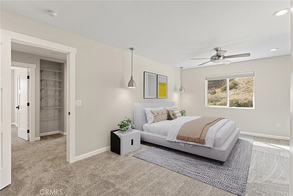 Bright primary bedroom with ceiling fan, designer lighting, and window framing canyon hill